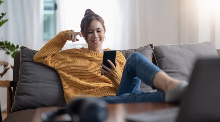 Woman smiling at her phone on the couch