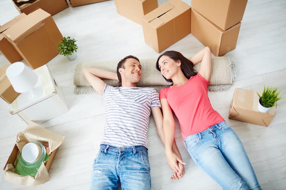 Young couple lying on the ground while moving house surrounded by boxes