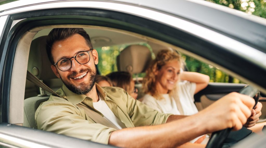 Happy family in their car with man behind the wheel