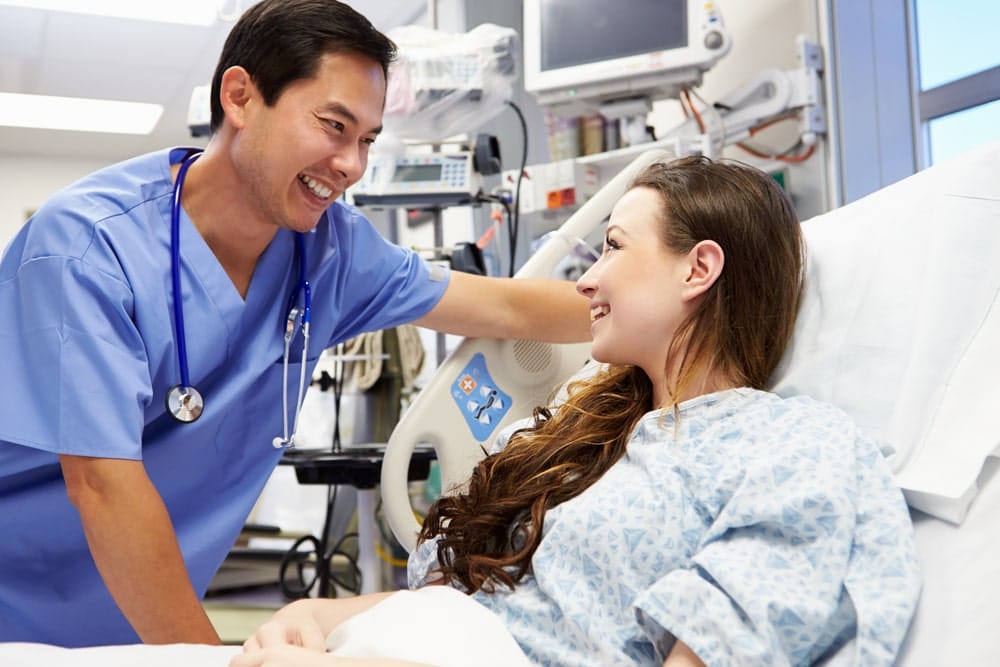Doctor smiling with a patient in her hospital bed