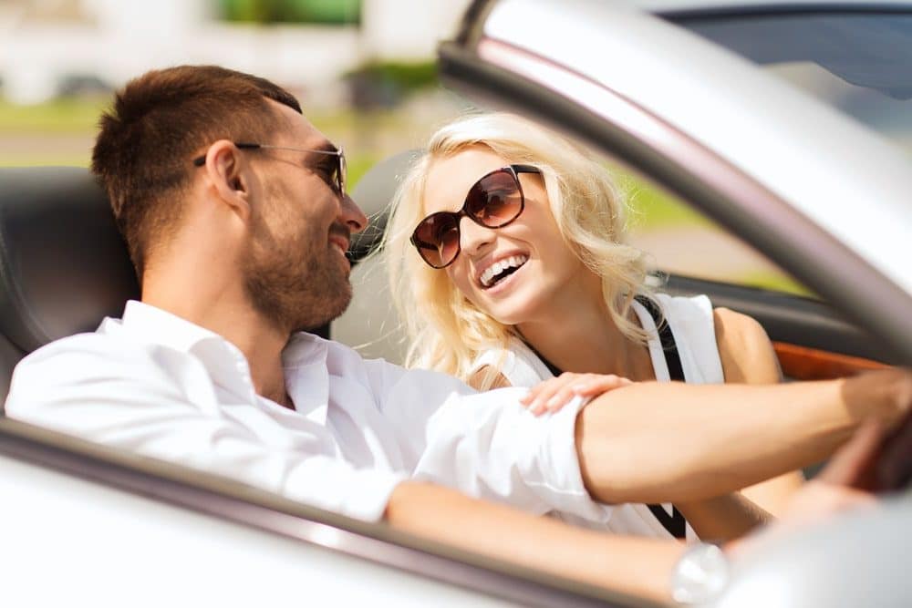 Car Insurance Banner - Couple driving in an open-top car, happy about receiving a no-claim bonus on their car insurance.