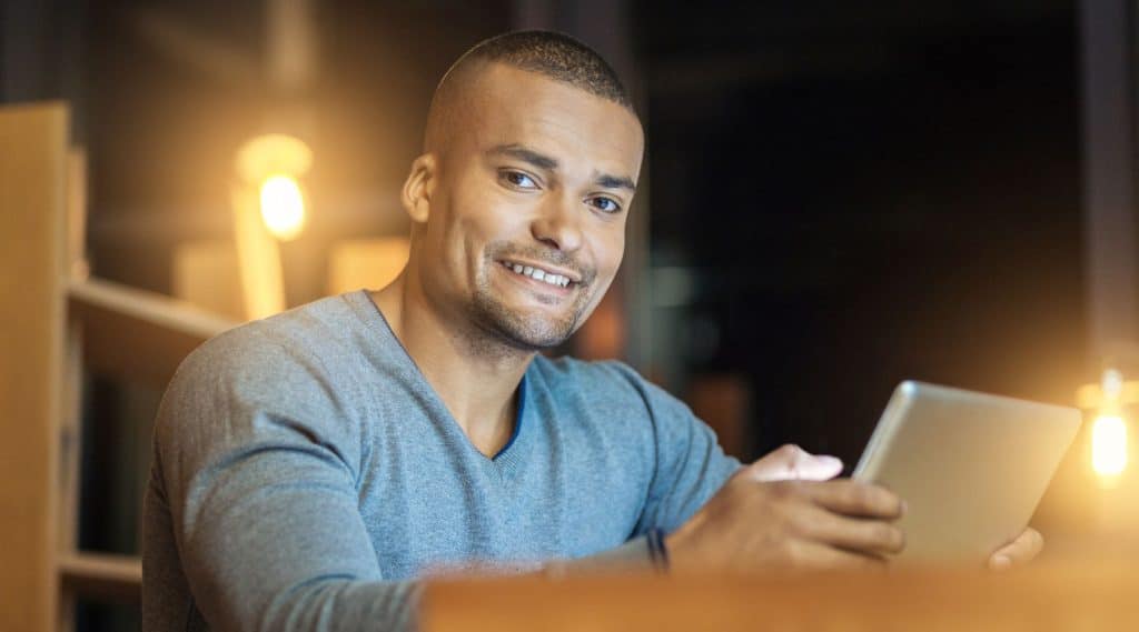 Man smiling while holding his tablet