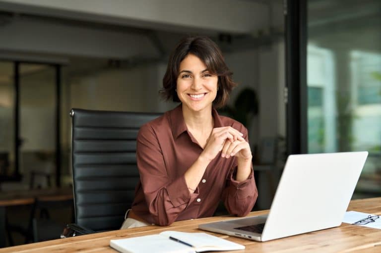 Businesswoman sitting at work desk with laptop