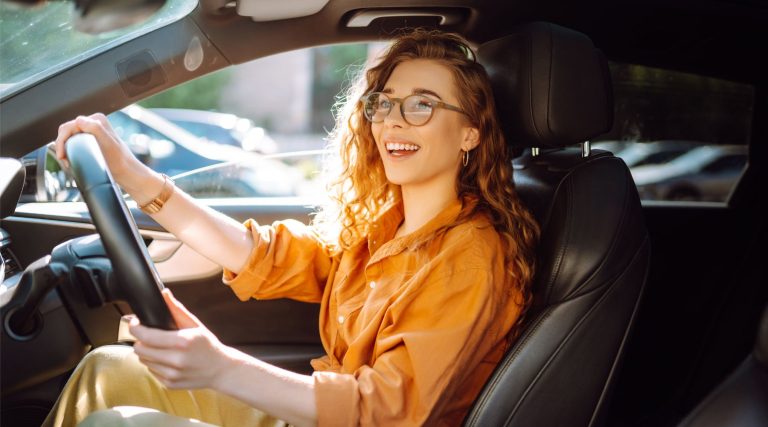 Happy woman in orange shirt driving her car