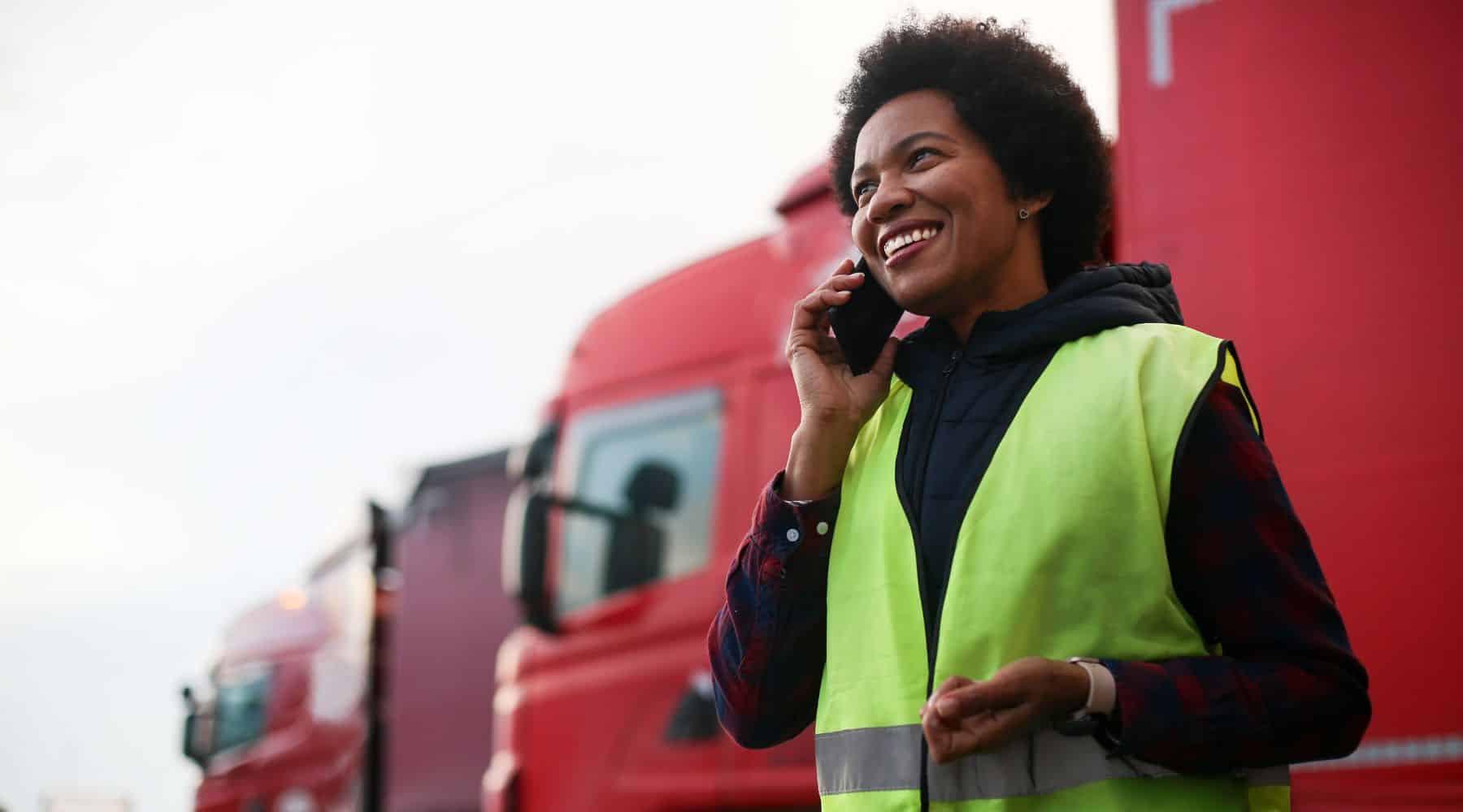 Woman on the phone standing in front of a fleet of red trucks