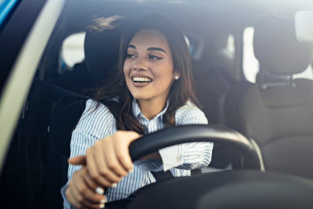 Young woman smiling while driving her car