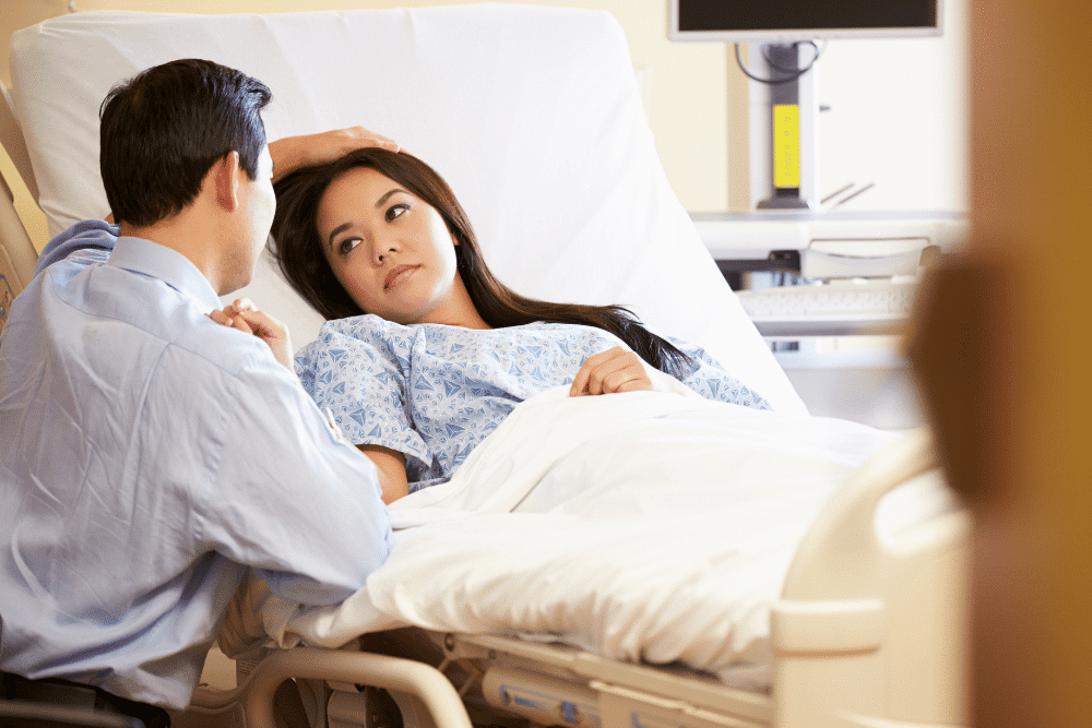 Woman lying in a hospital bed looking at her partner by her side