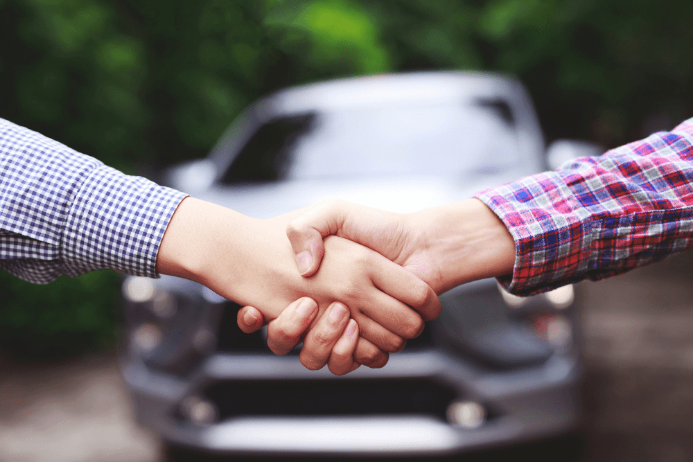 Handshake in front of a car after a private used vehicle sale